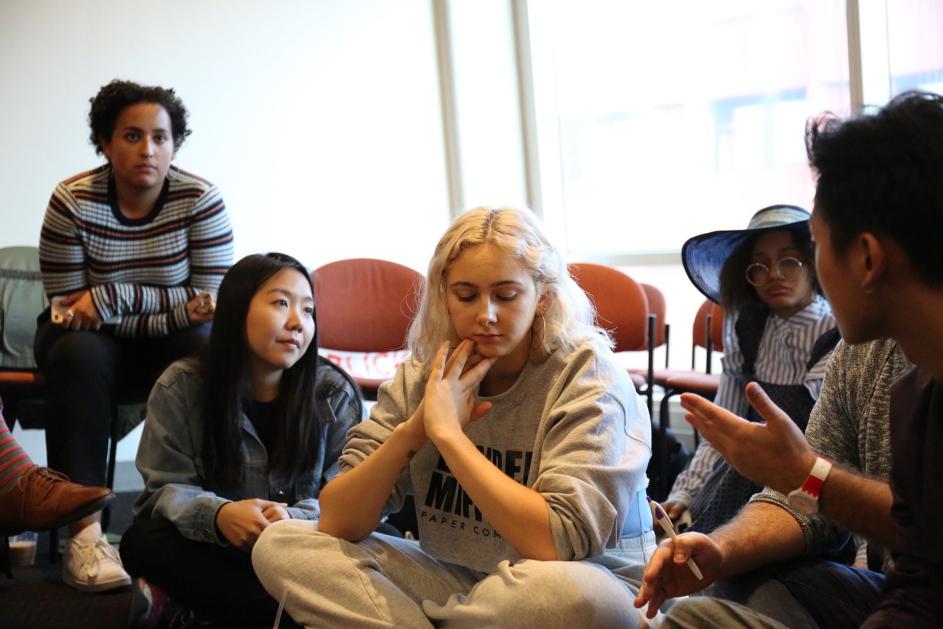 Four students sit on the floor and one sits in a chair above them